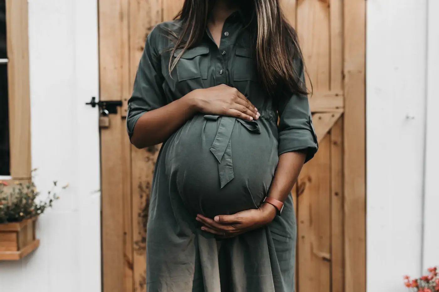A pregnant woman framed in a doorway, side light